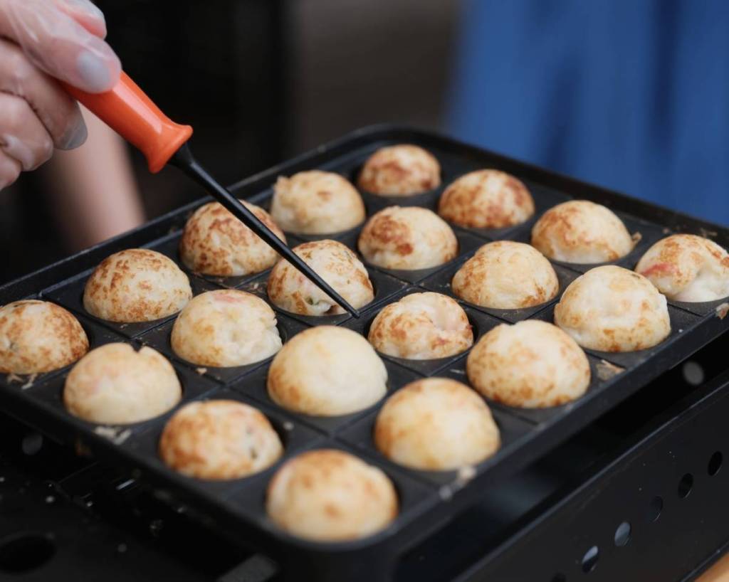 pequenas bolinhas douradas de massa a fritar numa frigideira grande