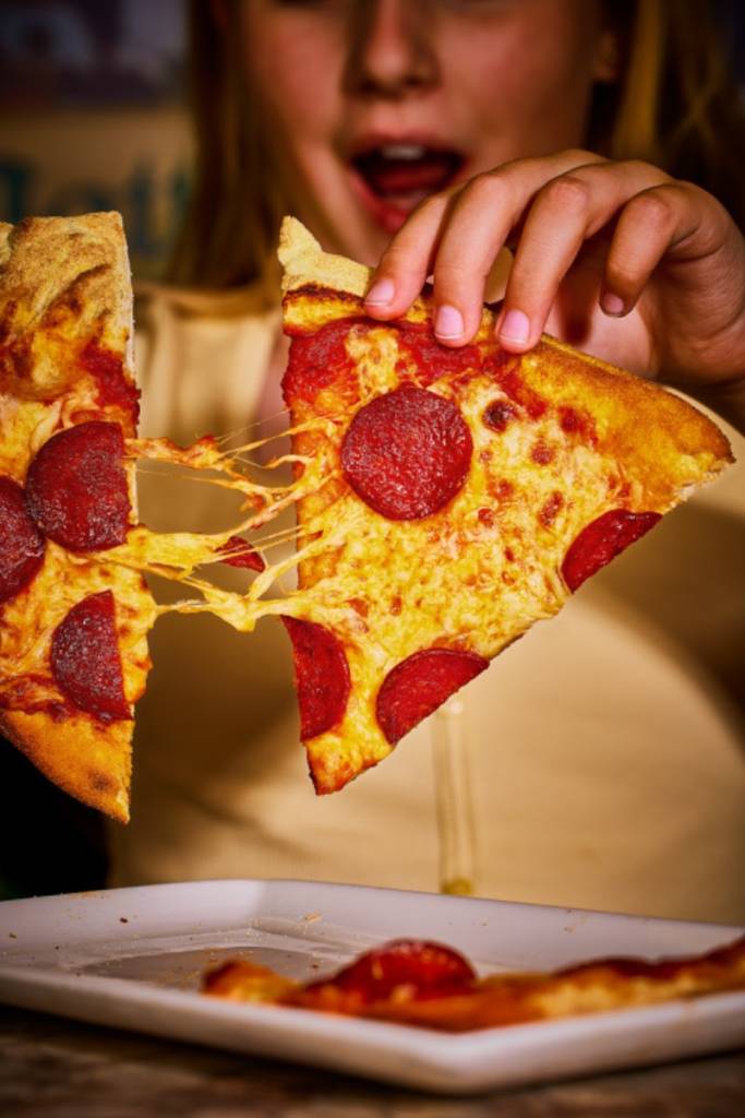 duas fatias de pizza a serem separadas, com o queijo derretido a esticar-se entre elas