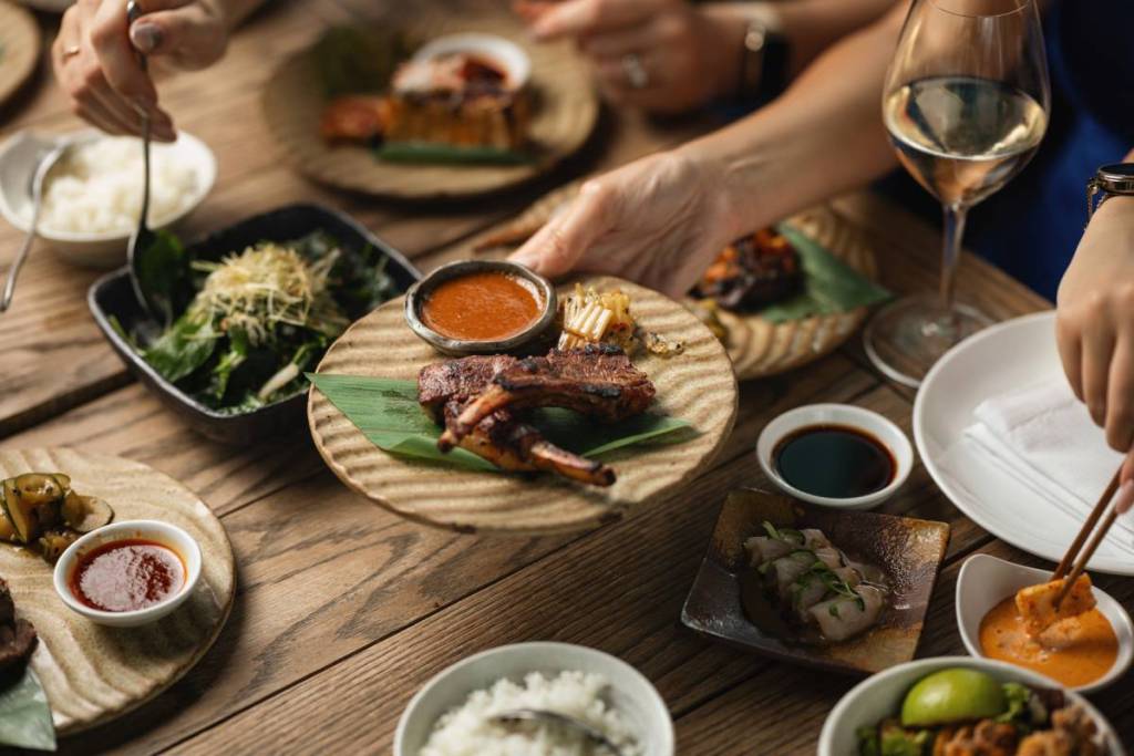 a plate of food being placed on a table covered in drinks and side dishes
