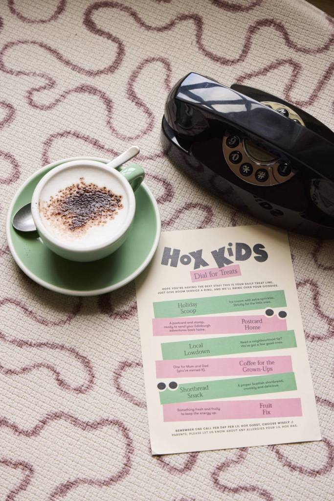 een kopje koffie naast een telefoon en een Hox Kids-menu
