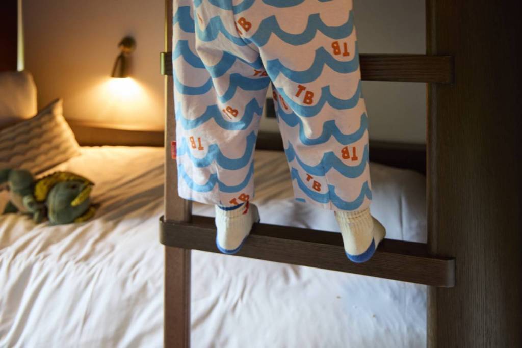 de beentjes van een kind die via een ladder in een stapelbed klimmen