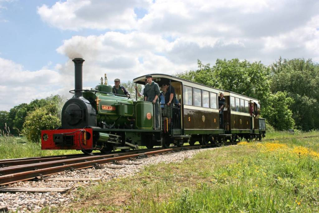 a small green train travelling through the countryside of tamworth