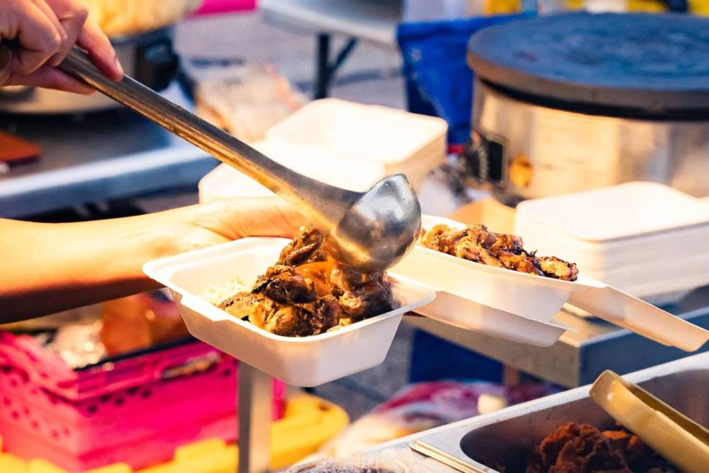 Karibisches Essen wird in eine Styropor-Takeaway-Box gepackt