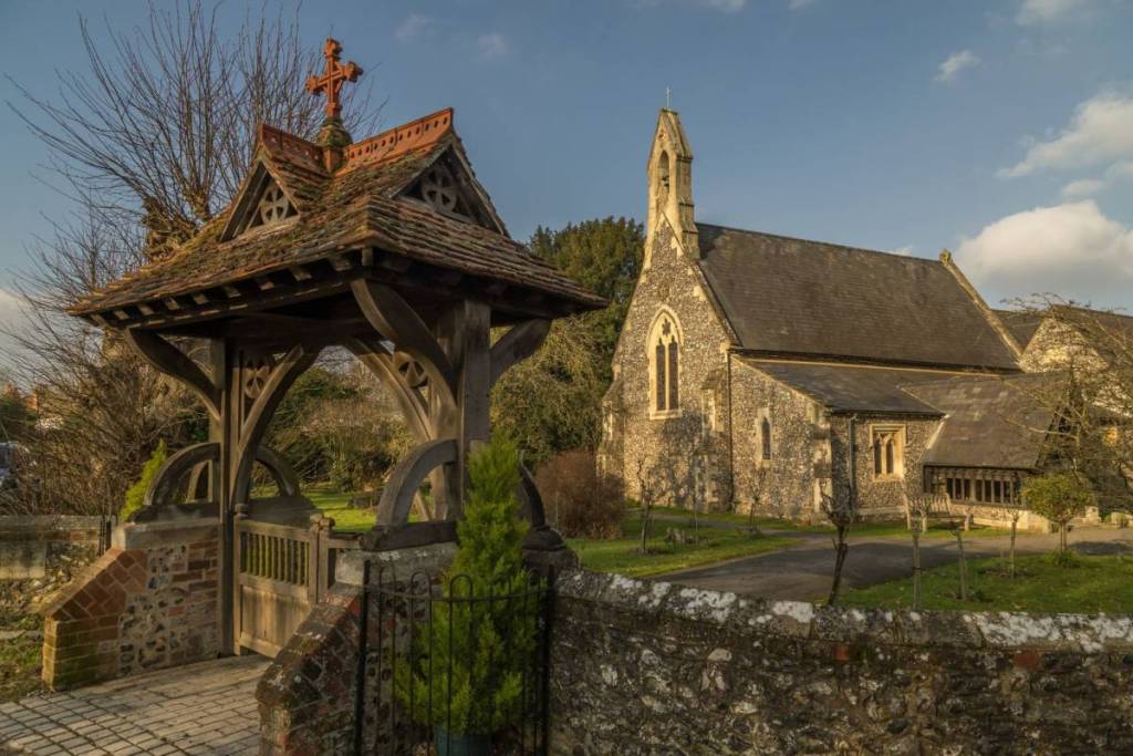 An old looking church with a gate in the foreground and a cross above. 