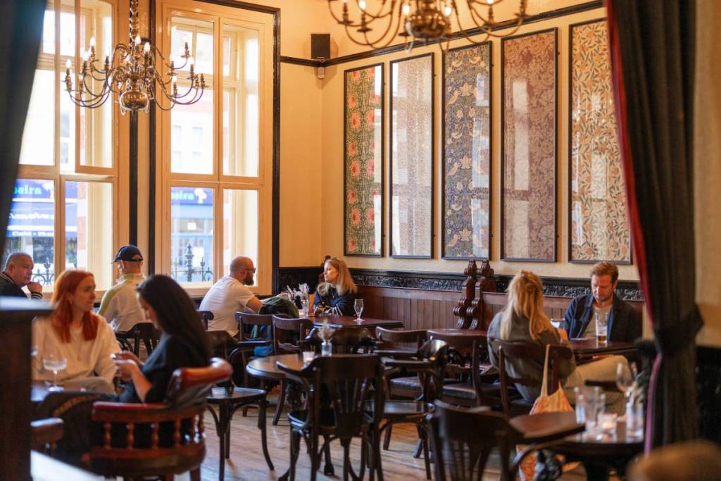 Een zitgedeelte in een pub met grote ramen die de ruimte met licht vullen