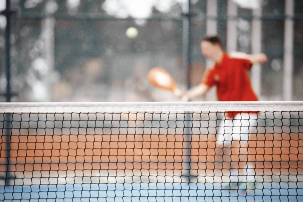 uma foto desfocada de um jogador de padel prestes a bater na bola