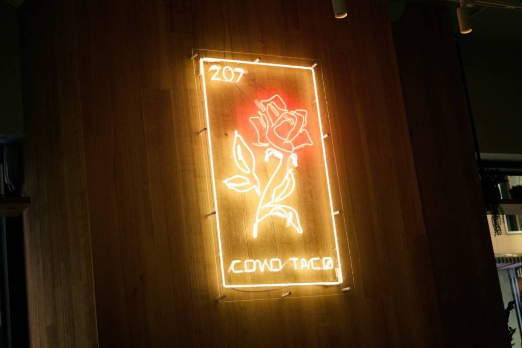 un'insegna al neon con il simbolo di una rosa, in un cocktail bar