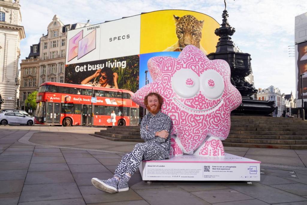 Ein Künstler stand vor einer mit Doodles verzierten Skulptur am Piccadilly Circus