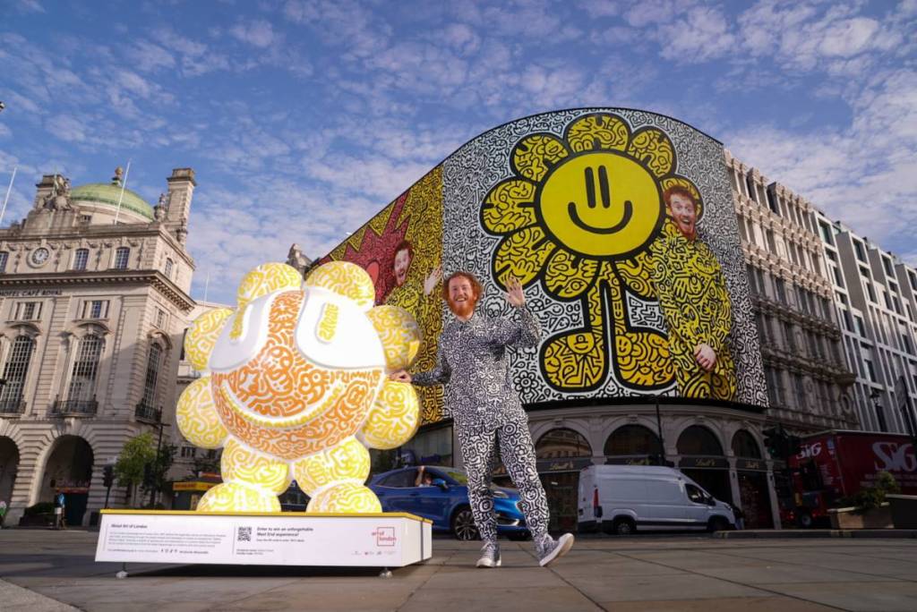 Ein Künstler stand neben einer mit Doodles verzierten Skulptur am Piccadilly Circus