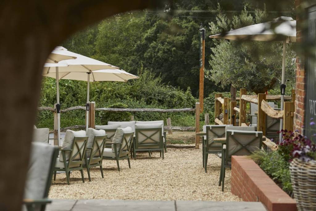 sillas y mesas en el jardín del pub de una posada histórica de Hampshire