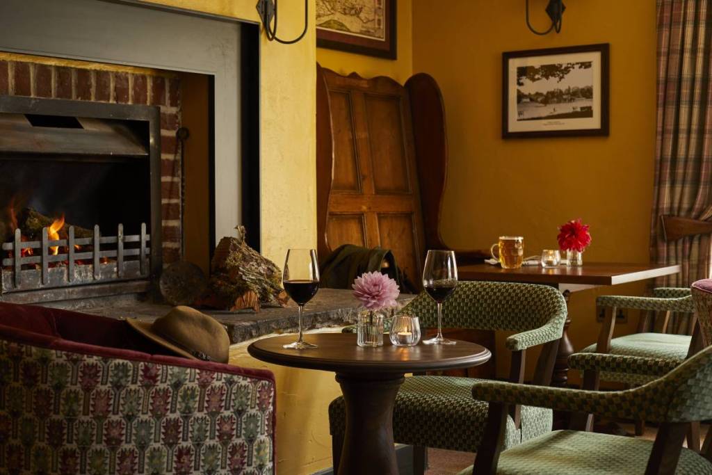 Una mesa en el interior de una acogedora posada con dos copas de vino tinto sobre ella
