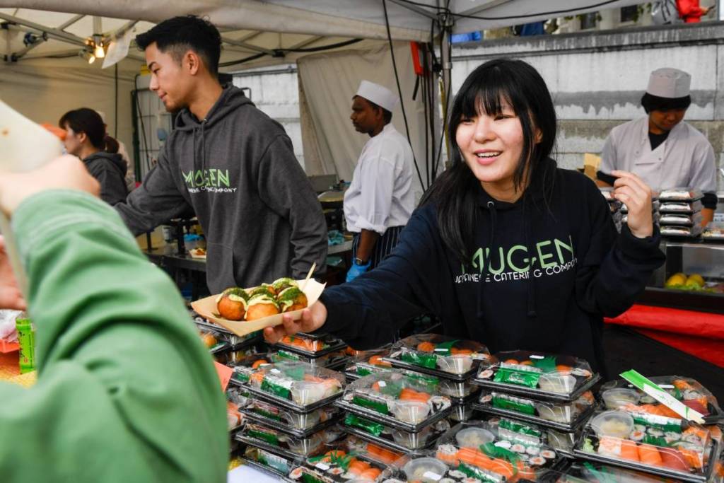 Iemand die Japans straatvoedsel serveert bij een festivalkraam