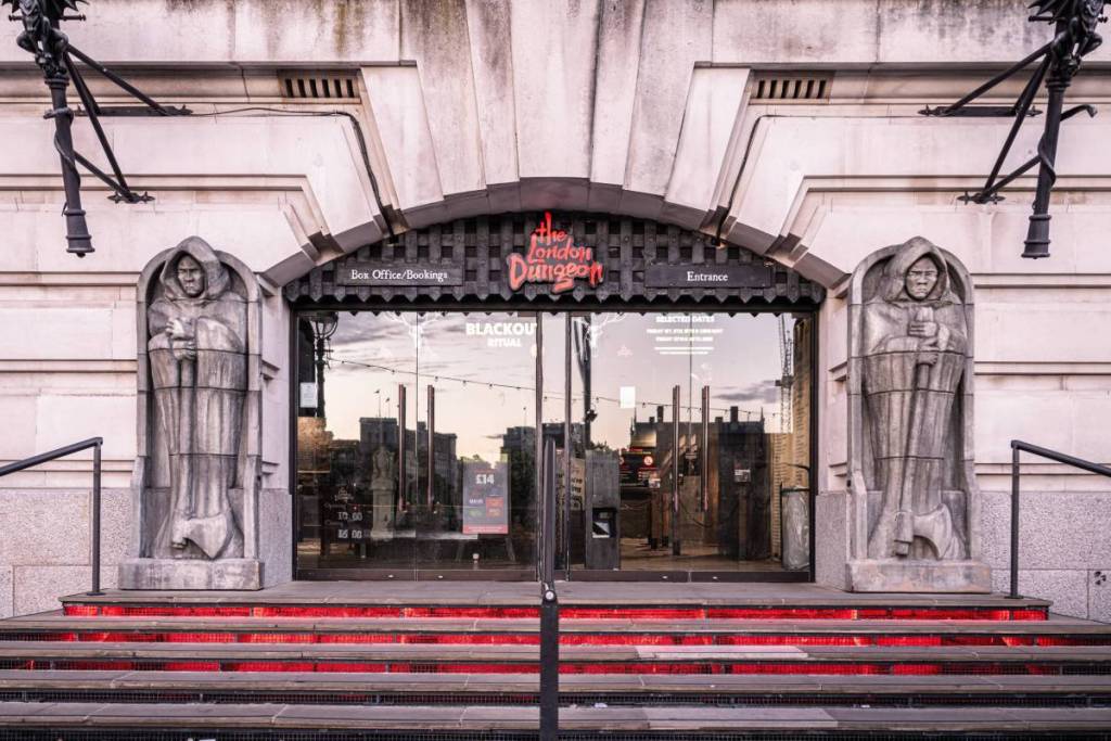 l’esterno dei London Dungeons con due statue di uomini incappucciati chinati sulle spade ai lati dell’ingresso in stile prigione sotterranea