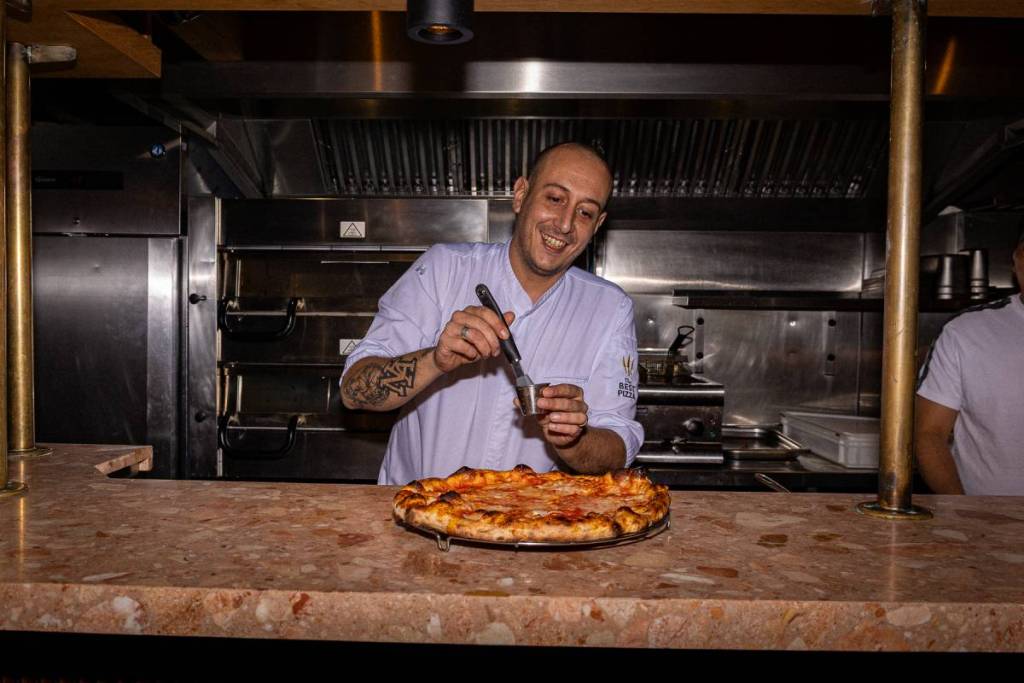 Pizzabäcker Andrea Asciuti, der einer Pizza den letzten Schliff gibt