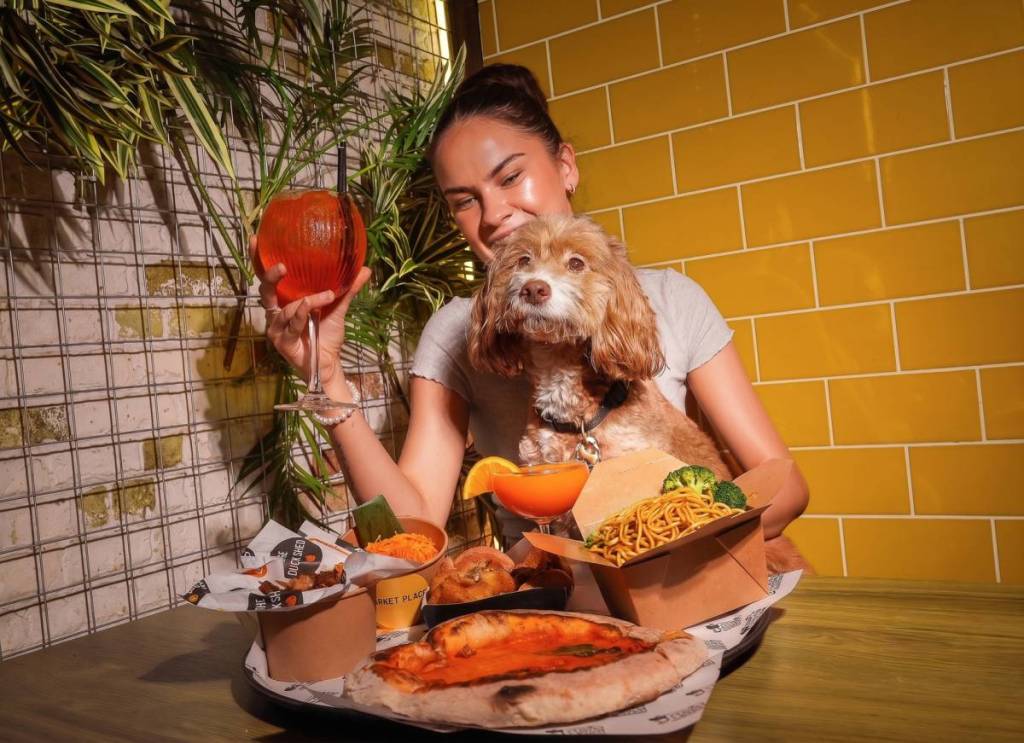 un perro y su dueño disfrutando de una bebida y una cena asada