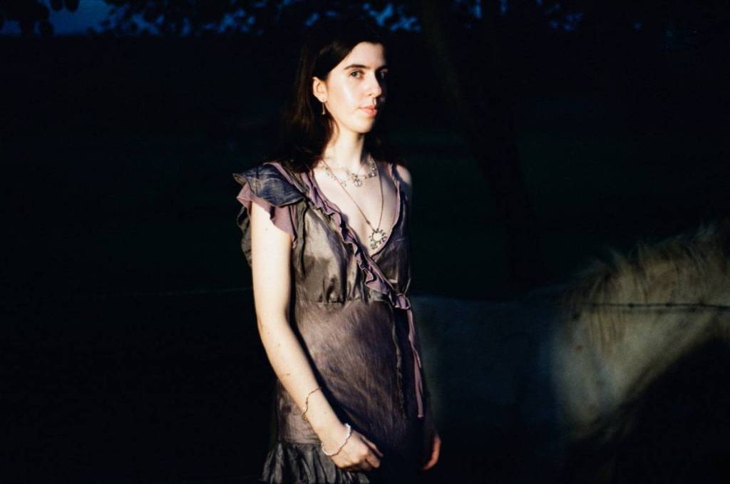 performer VERA SACRA standing in a field in a dress