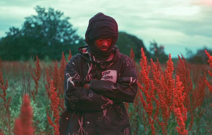 performer FREDDY FORBIDDEN standing in a field lit by a red glow