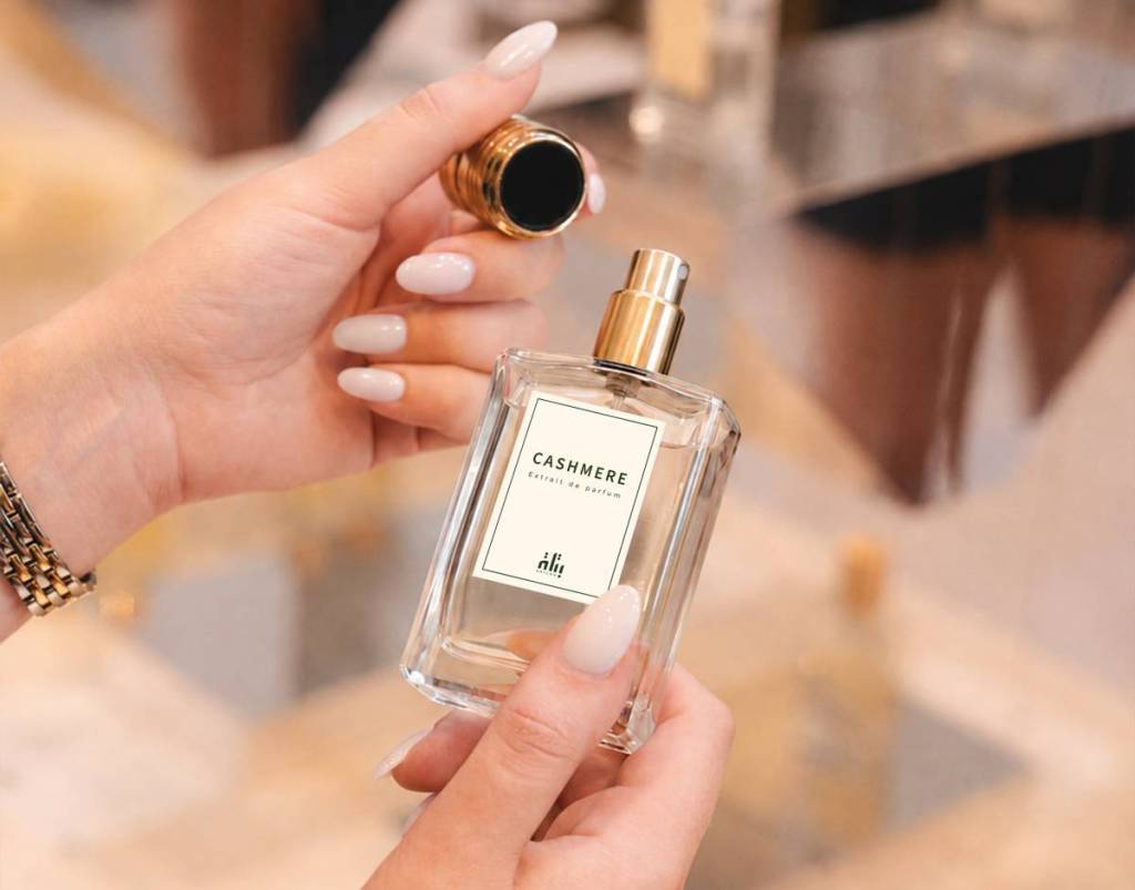 hands lift the lid from a batlah perfume bottle