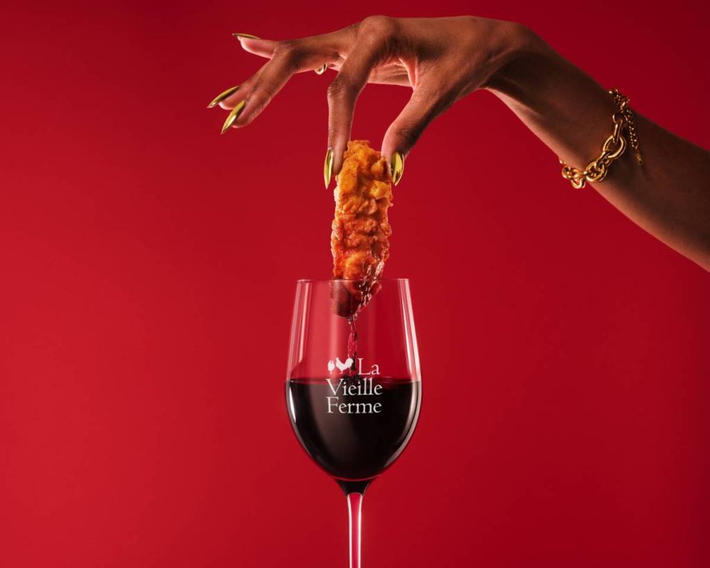 un morceau de poulet tendre sur le point d’être trempé dans un verre de vin