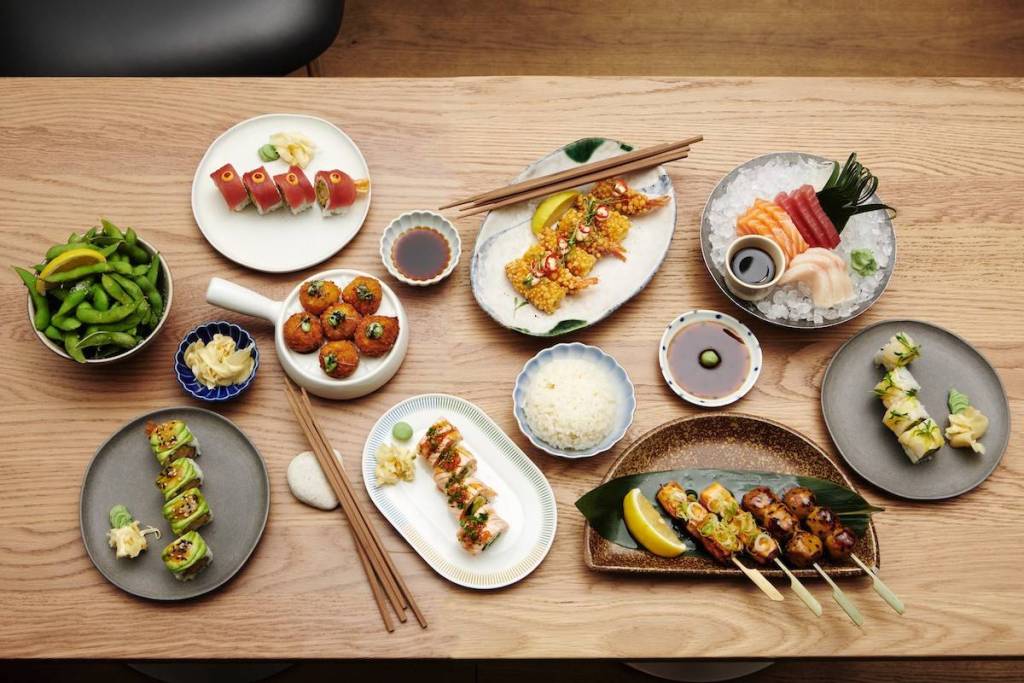 a flat lay photo of a tabletop full of sushi and japanese dishes 