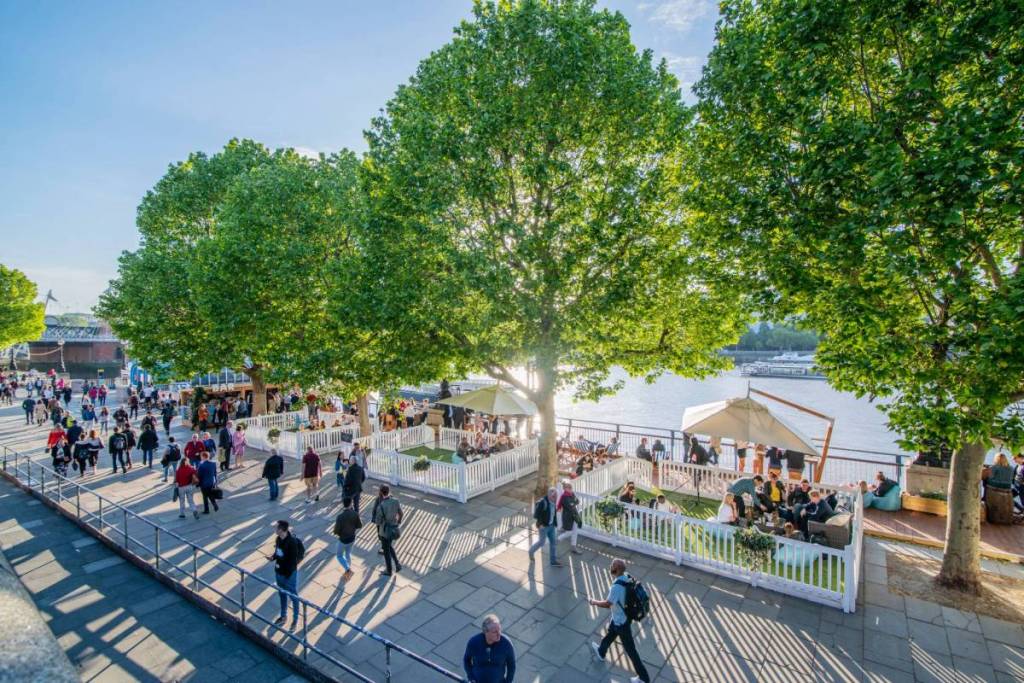 photo of the southbank looking out towards the river with people walking about and sitting in chill out spaces 
