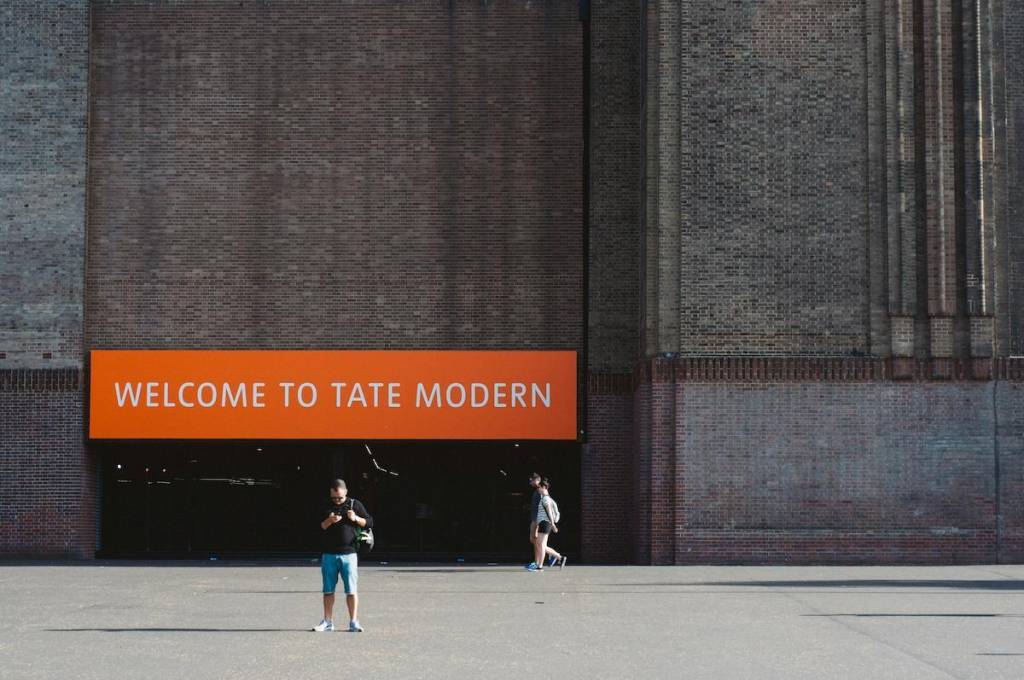 exterior of the tate modern with an organe 'welcome to the tate modern' sign over the entrance