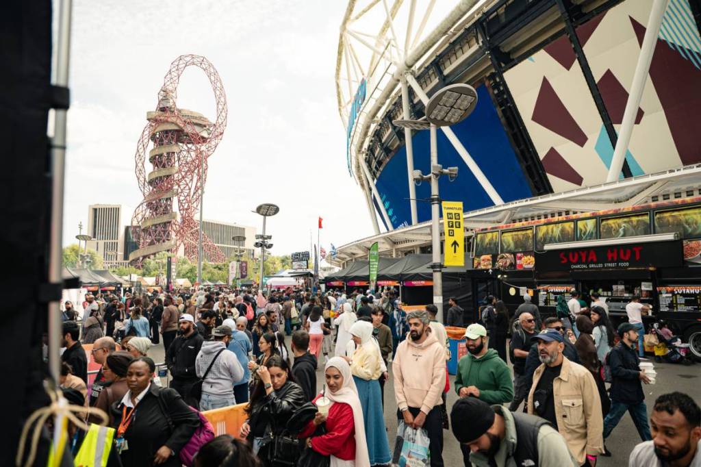 multidões de pessoas a fazer fila nas barracas de comida à porta do Estádio de Londres, com o icónico escorrega ArcelorMittal Orbit visível ao fundo