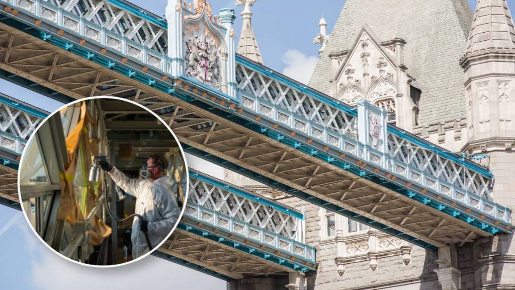 Een foto van het loopbruggetje van de Tower Bridge met iemand die boven het brugdek een hittewerende behandeling aanbrengt op de glazen ruiten
