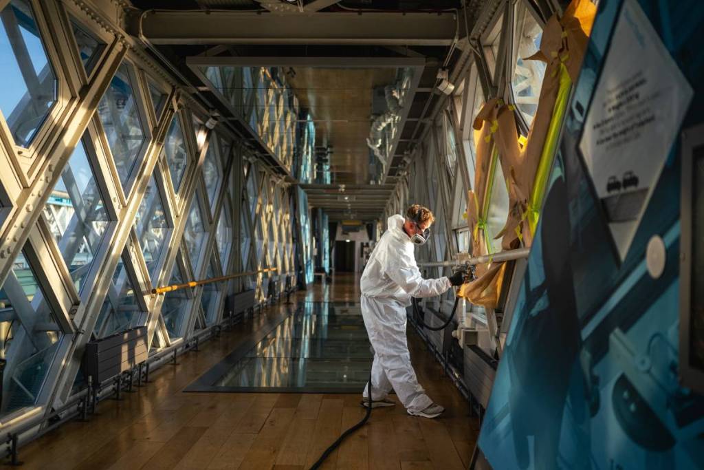 Iemand die een behandeling aanbrengt op het glas van de hooggelegen loopbrug van de Tower Bridge