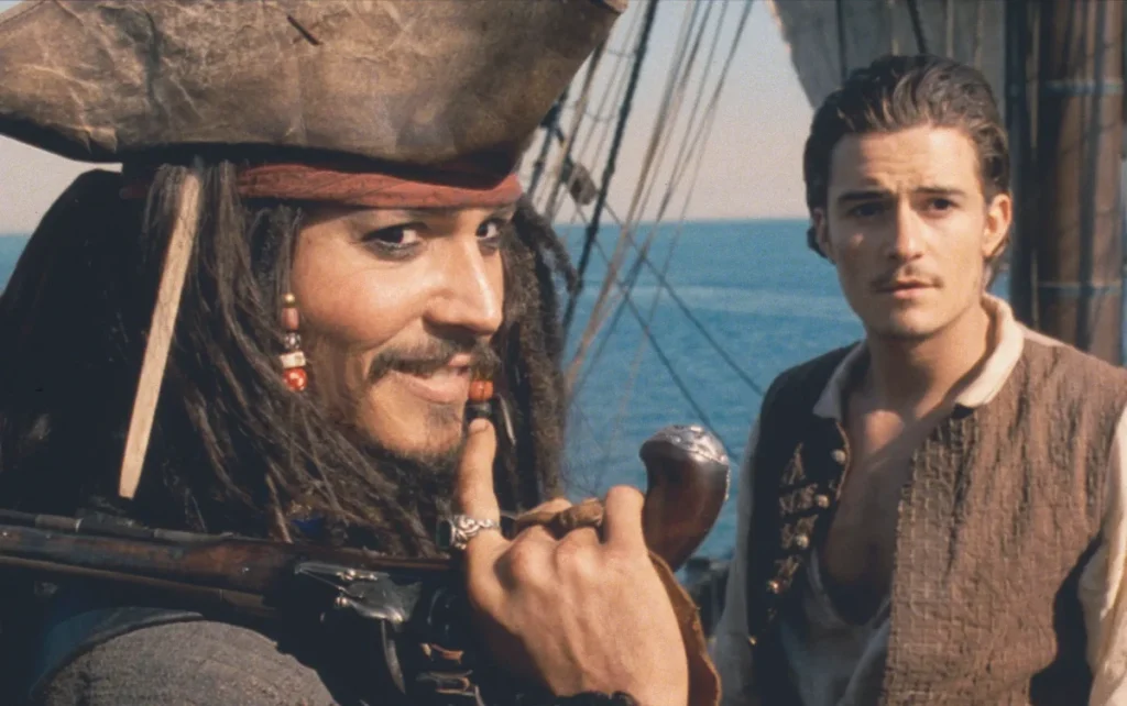 un fotogramma da “Pirati dei Caraibi: La maledizione della prima luna” che mostra Jack Sparrow con aria subdola e Will Turner