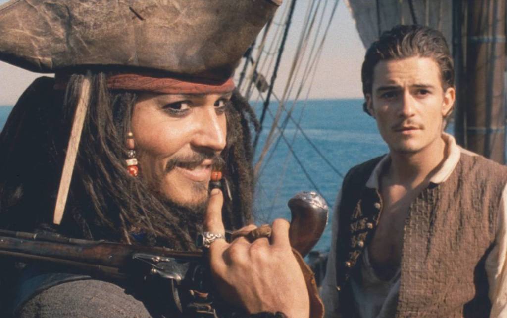 a still from Pirates of the Caribbean: The Curse of the Black Pearl showing Jack Sparrow looking devious and Will Turner