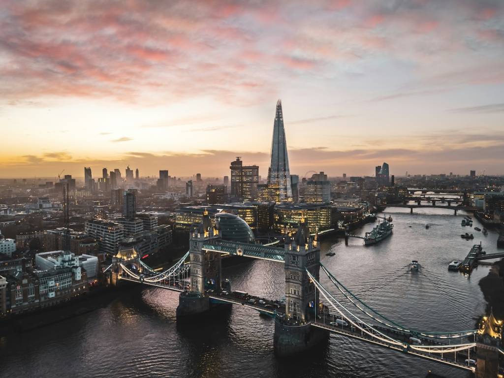 the view of the london skyline at sunset, the shard and tower bridge clearly visible against a pink sky