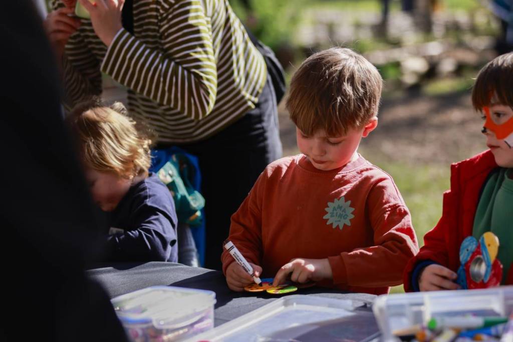 a group of children take part in an arts and crafts workshop outside at the Woodland Festival in Dulwich Wood