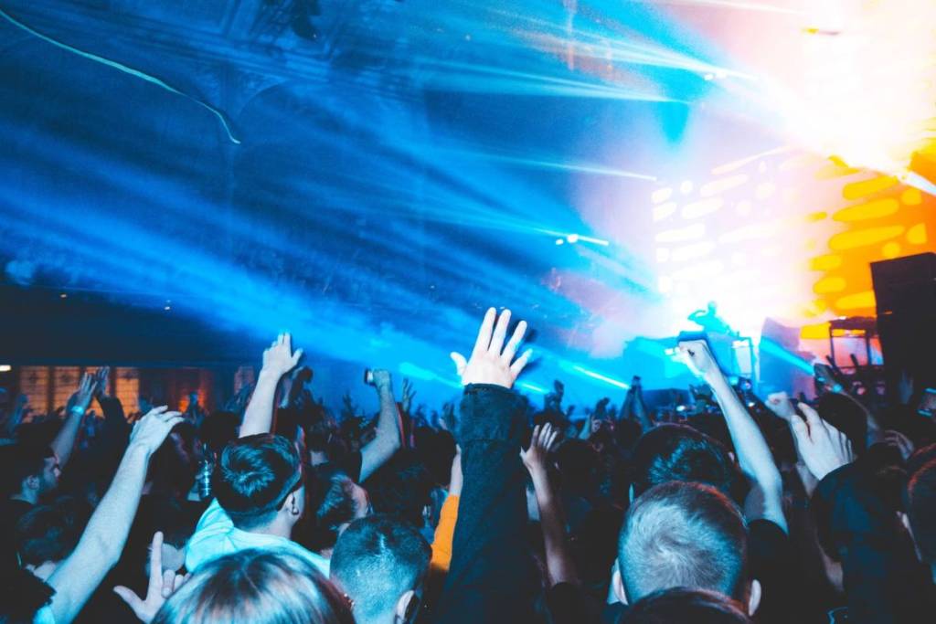 a crowd at a music venue have their hands in the air at a gig