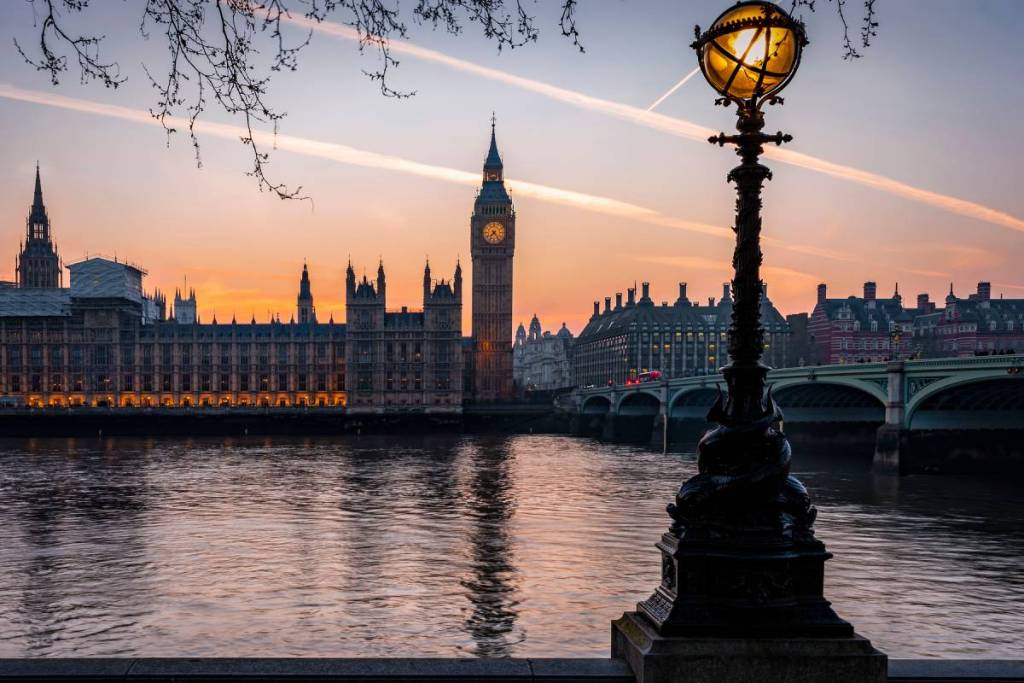 The Westminster Palace and Elizabeth Tower in London, during a calm sunset with street light and orange sky