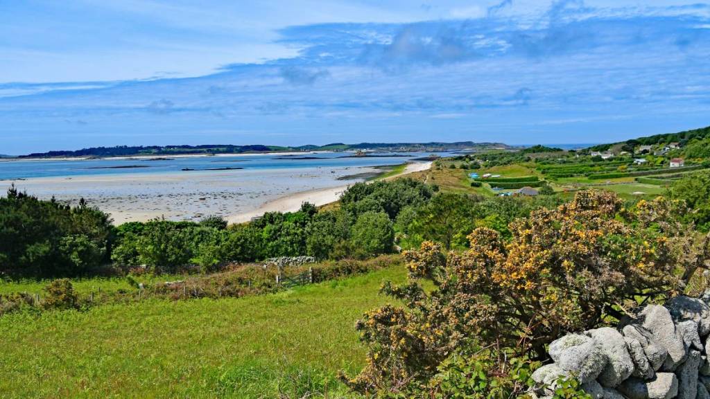 Prachtig groen en zonnig uitzicht over het eiland St Martin’s op de Scilly-eilanden, met in de verte de blauwe zee en de blauwe lucht
