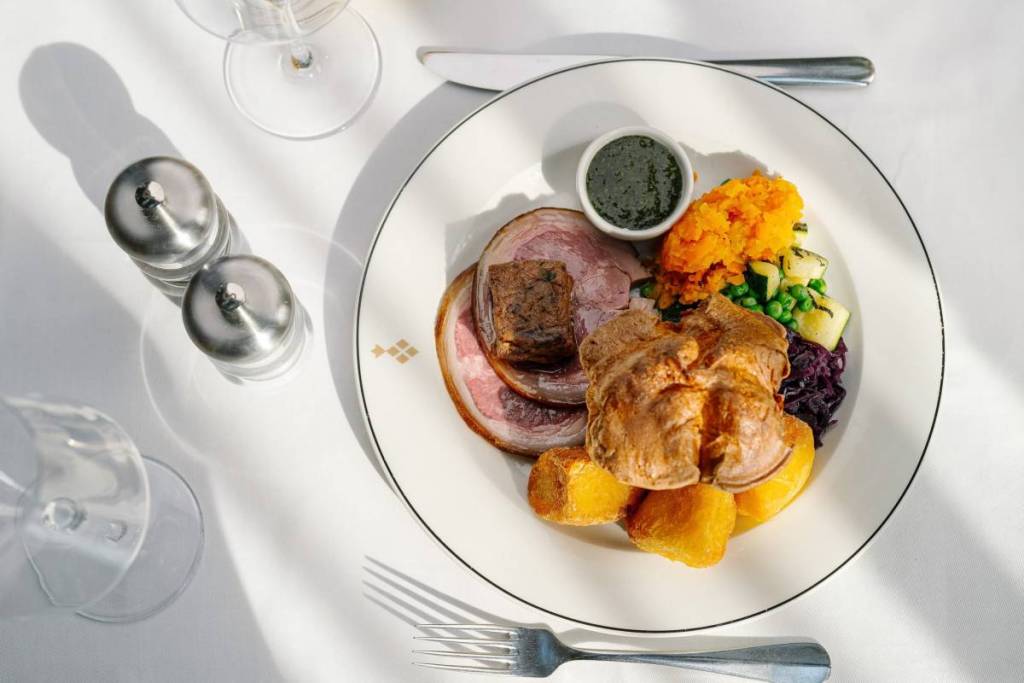 een zondagse roast met alles erop en eraan op een schaal op een wit linnen tafelkleed