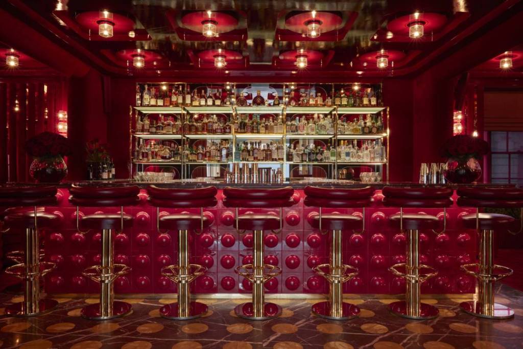 il bar dai toni rossi di Langan’s, con sgabelli rossi e lampade a sospensione