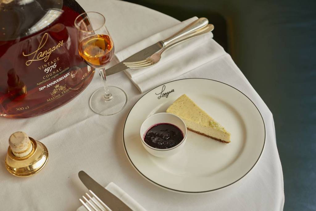 cheesecake accanto a una bottiglia di cognac su una tovaglia bianca
