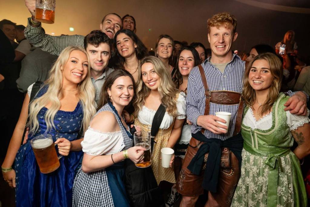 una folla di persone vestite in stile tedesco, con in mano delle pinte, durante una festa dell’Oktoberfest