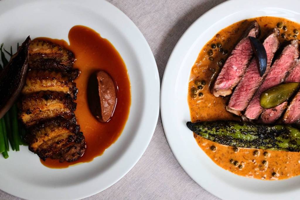 due piatti dai colori vivaci, entrambi ricchi di salsa, con proteine affettate e contorni di verdure