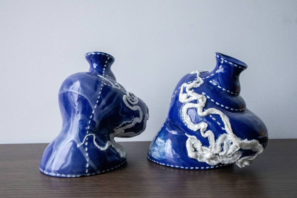 due vasi in ceramica astratti, blu e bianchi, ricchi di dettagli, che sembrano inclinarsi e ondeggiare grazie alle forme sinuose e ai bordi curvi