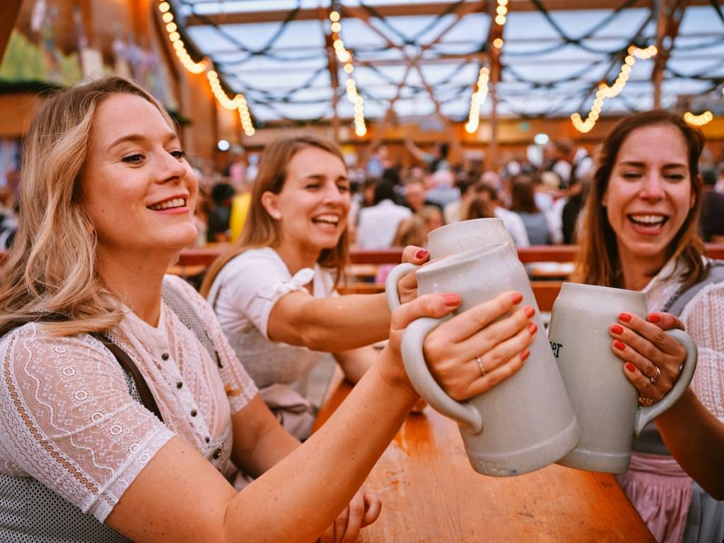 A group of women cheersing pints of beer in an Octoberfest tent