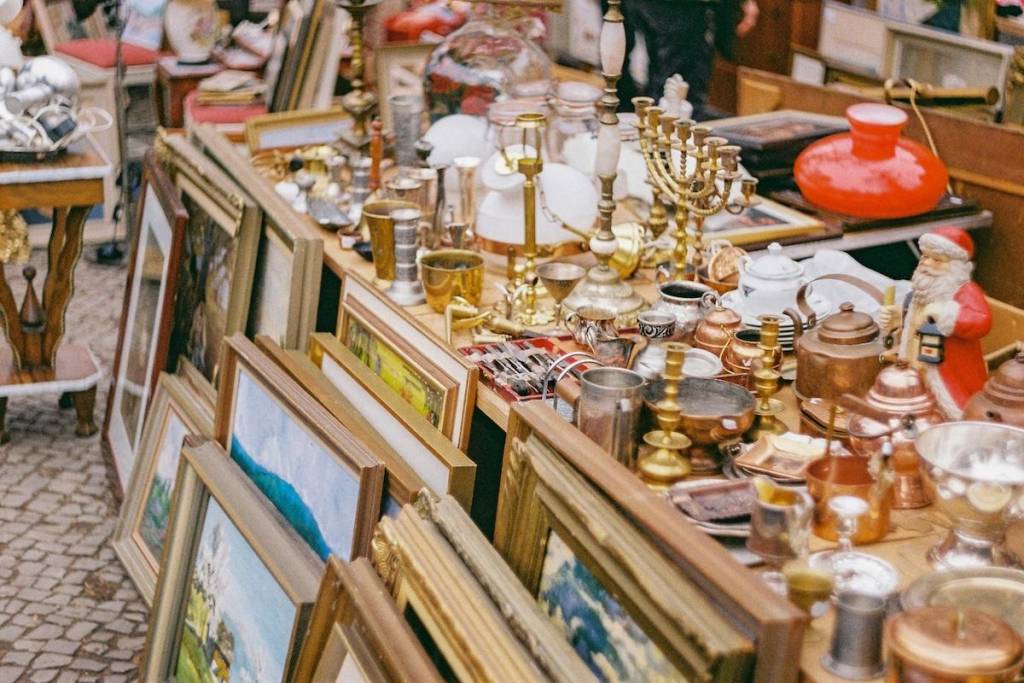 A market table crowded with vintage homeware and paintings