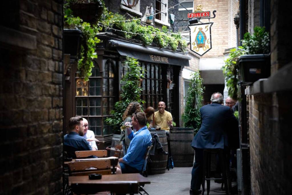 la gente sedeva a bere all’aperto davanti al pub “Ye Olde Mitre”, in un vicolo di Londra
