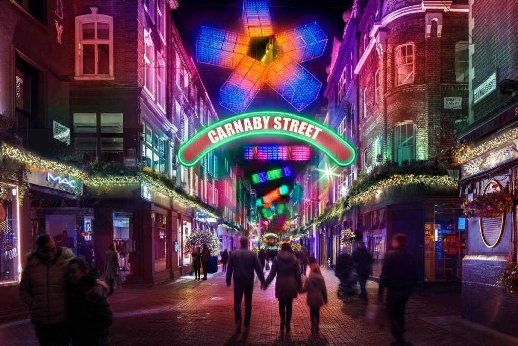 een afbeelding van mensen die onder verlichte geometrische vormen in de lucht boven Carnaby Street lopen, en een verlicht bord met de tekst ‘Carnaby Street’