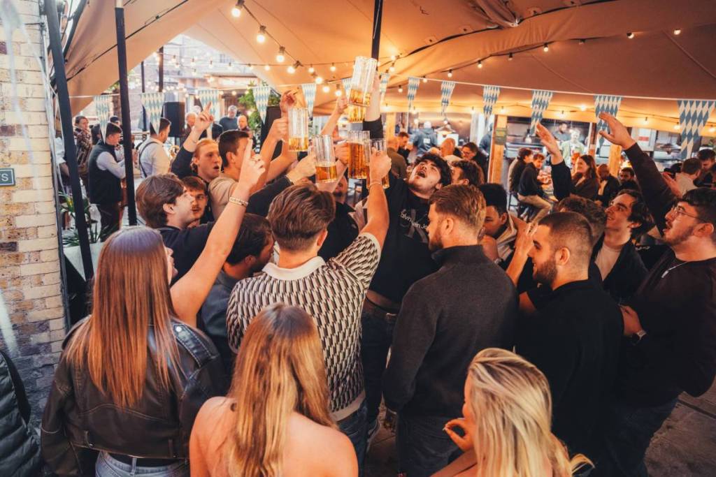 Eine jubelnde Menschenmenge, von hinten gesehen, bei einer Oktoberfest-Party am Flat Iron Square in London