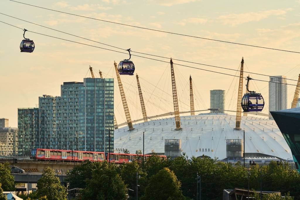Cable cars are crossing in front of a yellow sunset in front of a London sky