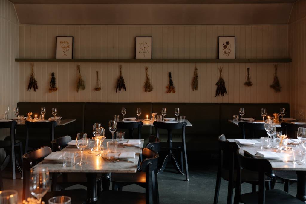 An empty dining room with candles lit on set tables