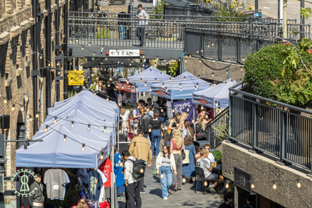 Menschen, die durch einen Straßenmarkt im Coal Drops Yard schlendern